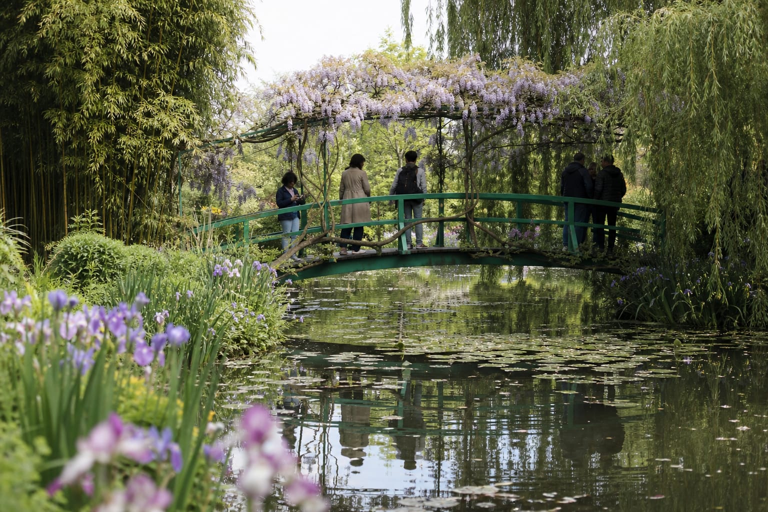 Pont japonais vert couvert de glycine au-dessus du bassin aux nymphéas du jardin de Monet à Giverny, un matin de mai