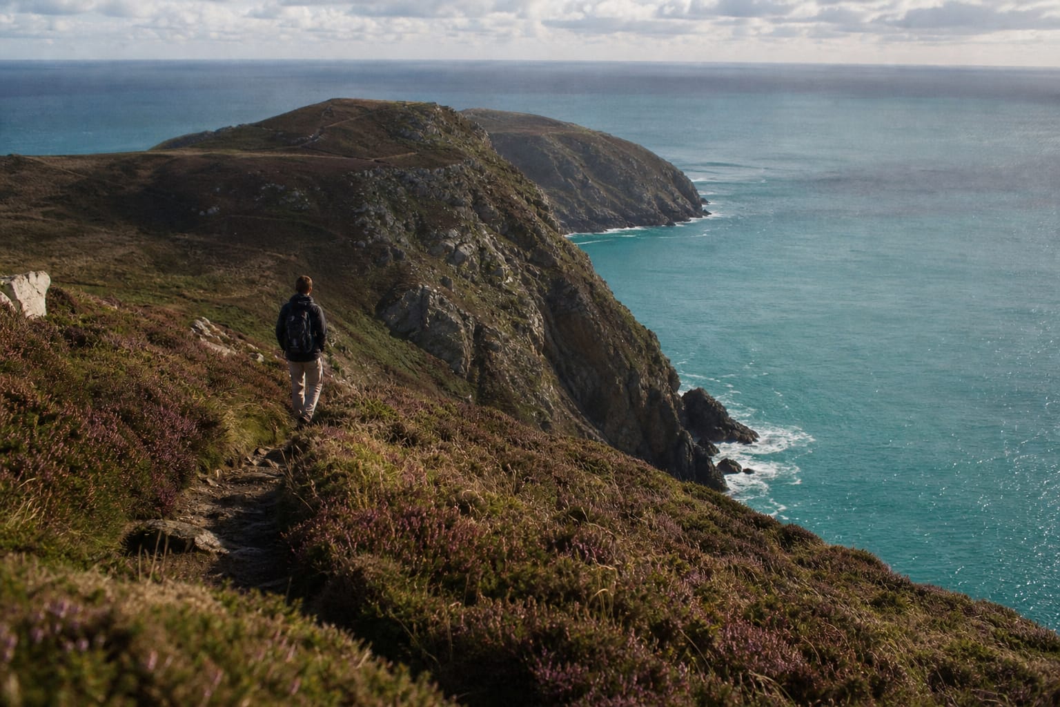 Pointe rocheuse couverte de lande au-dessus d'une mer turquoise sur la presqu'île de Crozon