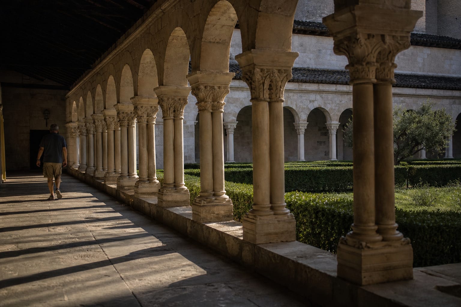 Cloître roman aux arcades de pierre claire baigné d'une lumière de fin de journée