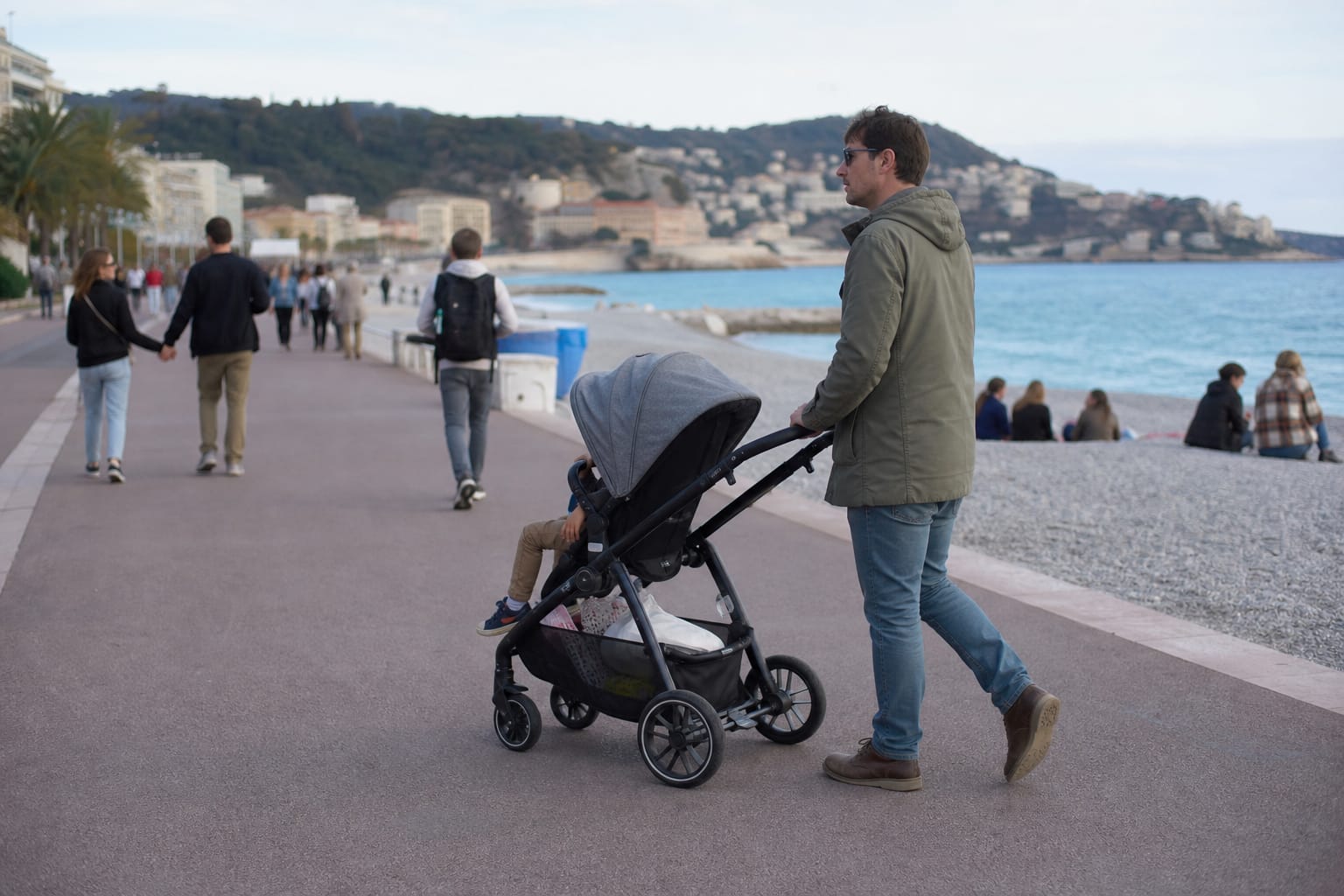 Parent poussant une poussette sur une promenade en bord de mer