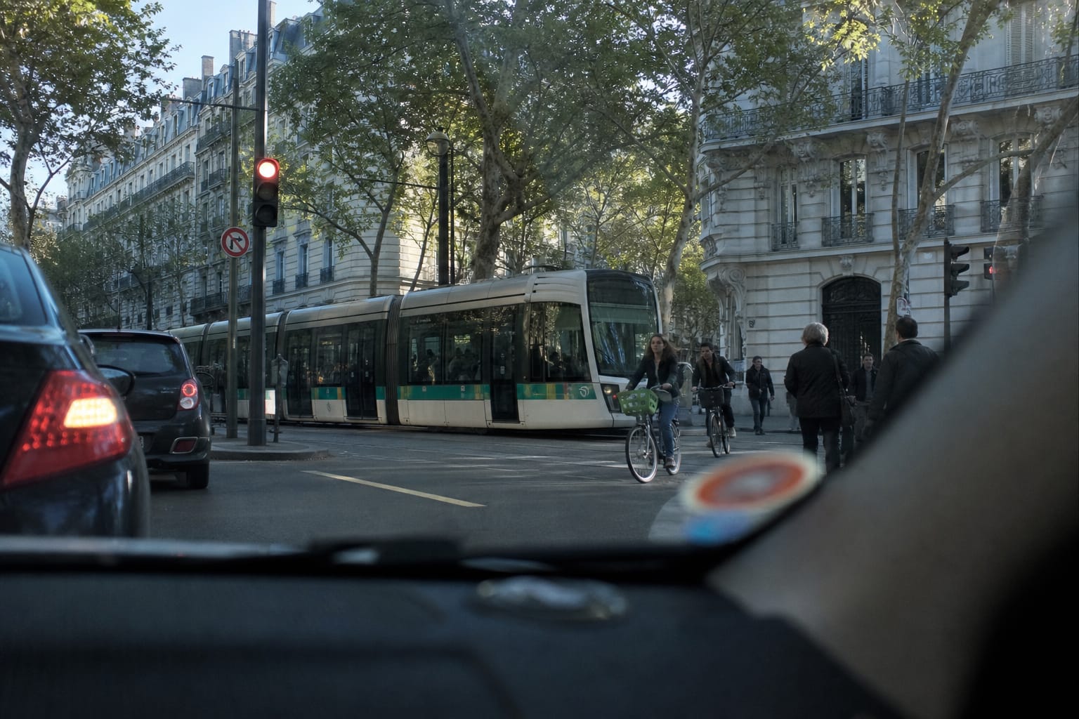 Petite vignette ronde colorée collée au bas d'un pare-brise, devant un boulevard urbain avec tramway et platanes