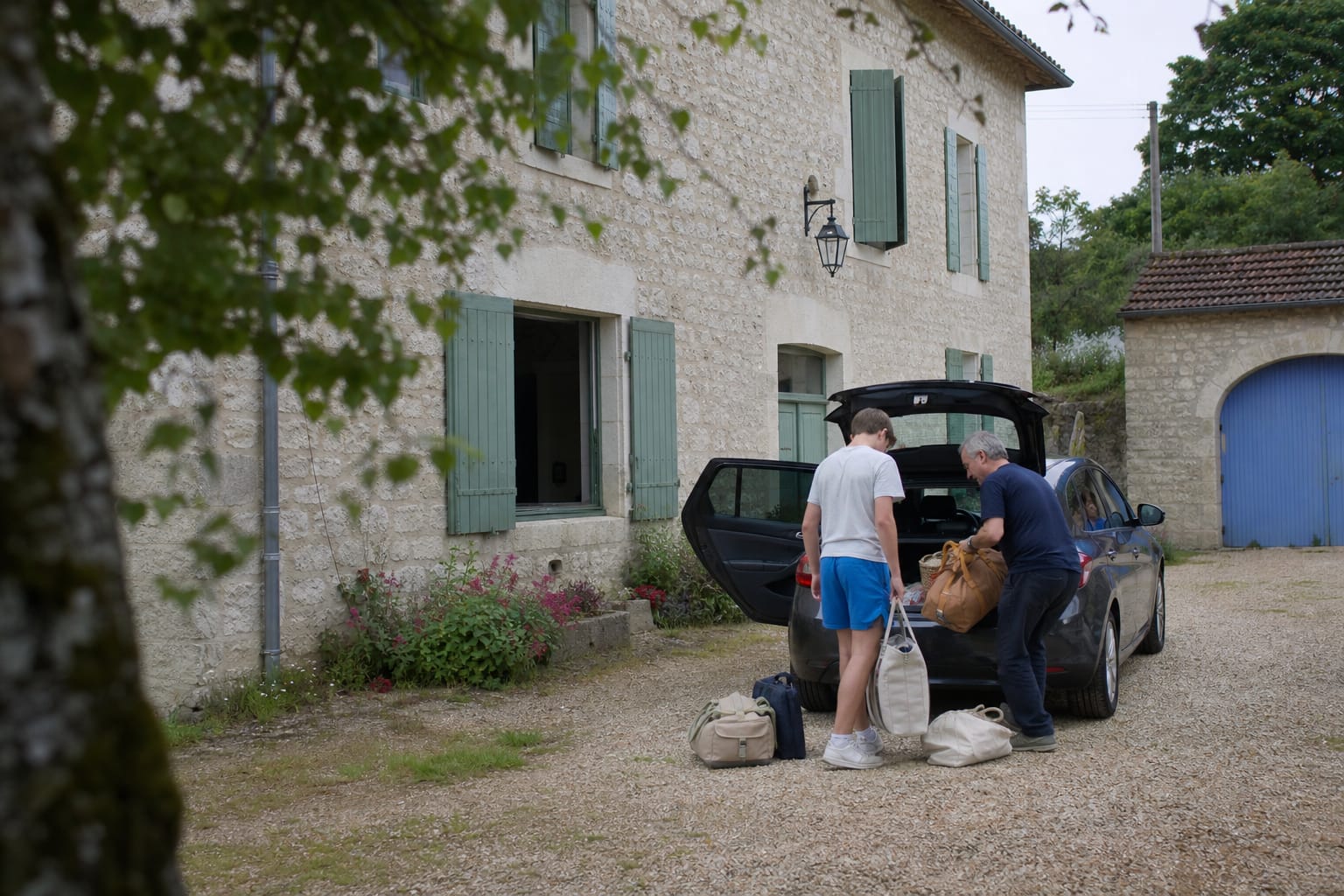 Voiture garée devant un gîte de campagne, bagages en cours de chargement