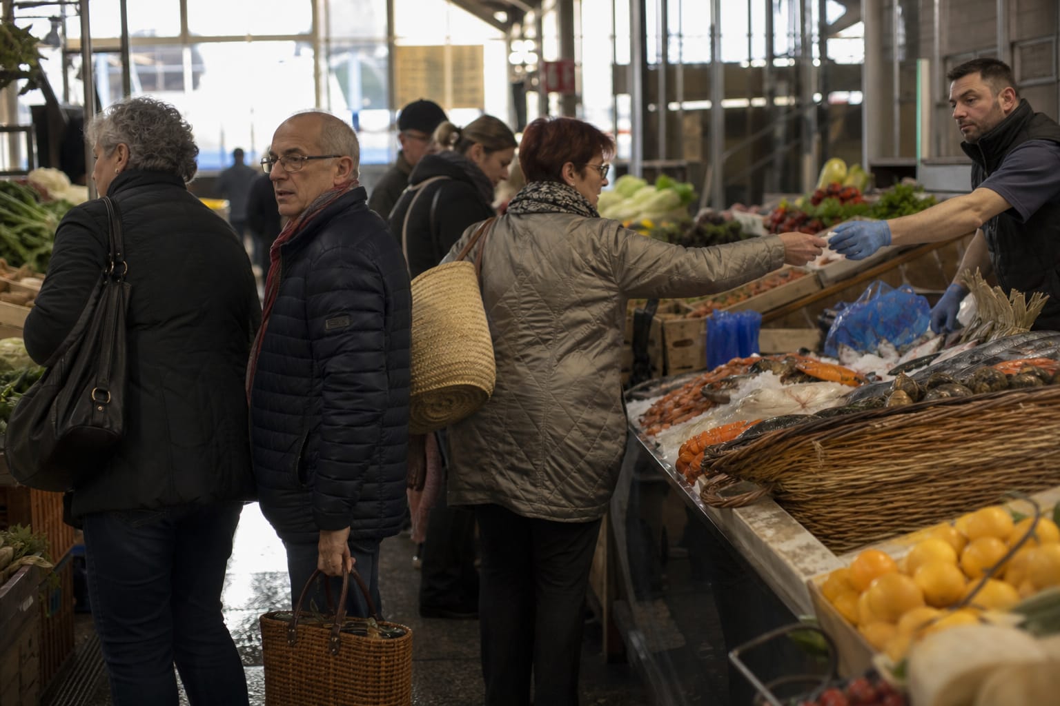 Étal de primeurs sous une halle métallique du XIXe siècle, clients et marchands