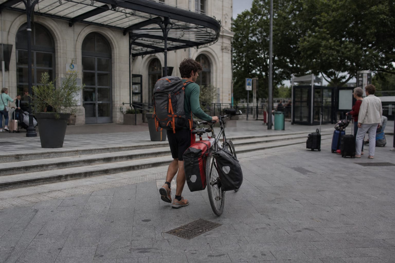 Voyageur à vélo quittant une gare avec ses bagages