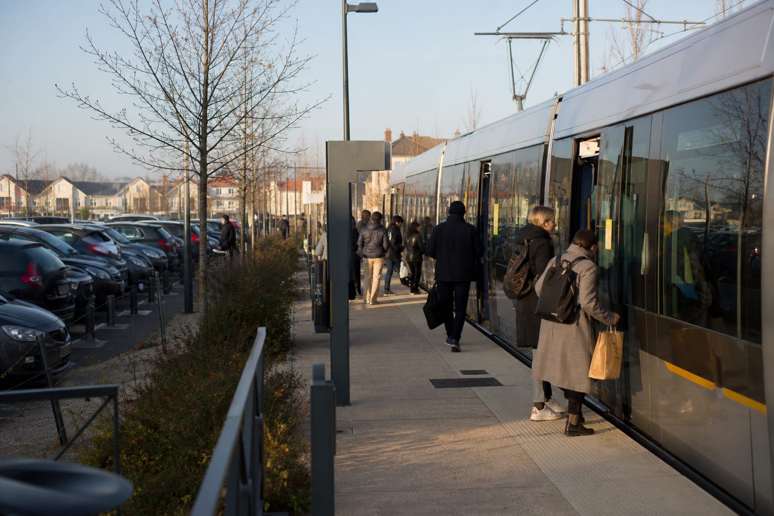 Parking relais en périphérie avec tramway à l'arrêt et voyageurs qui embarquent