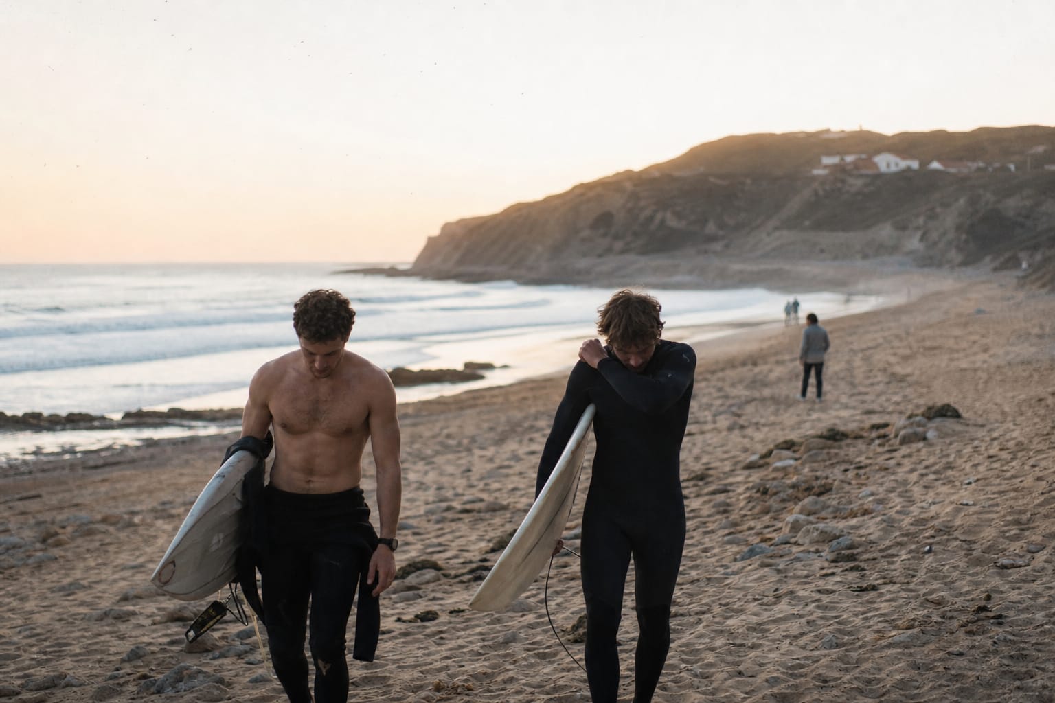 Surfeurs remontant la plage avec leur planche en fin de journée
