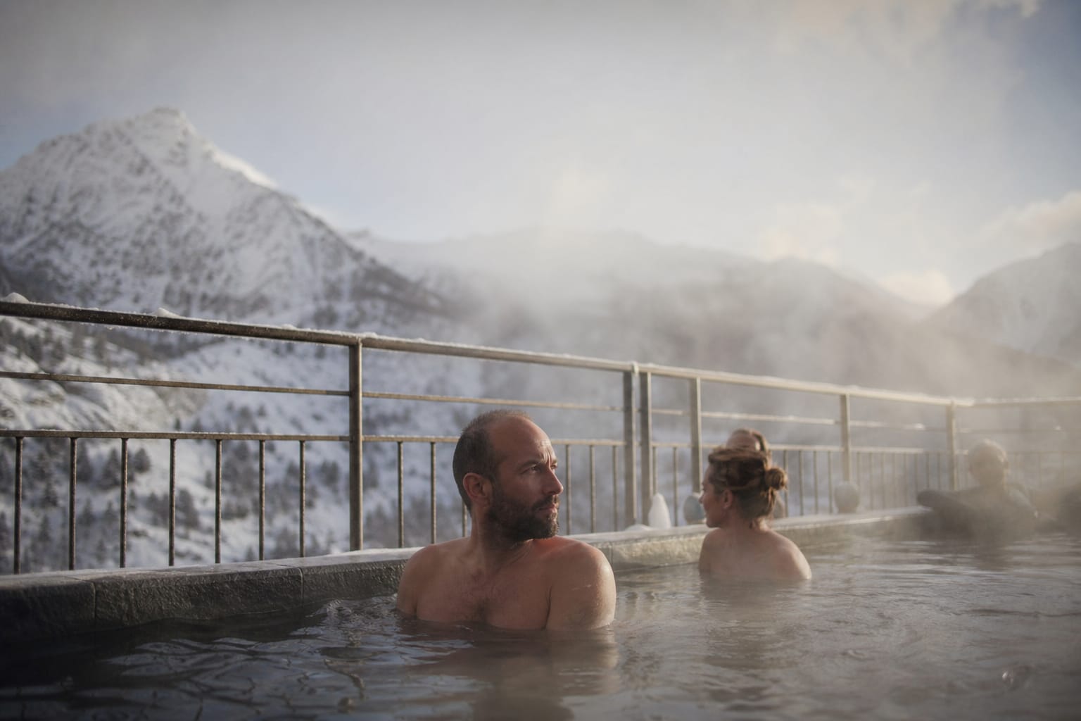 Bassin thermal extérieur fumant avec vue sur la montagne en hiver