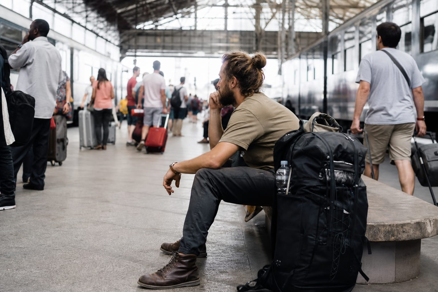 Voyageur au long cours assis sur un quai de gare avec un grand sac