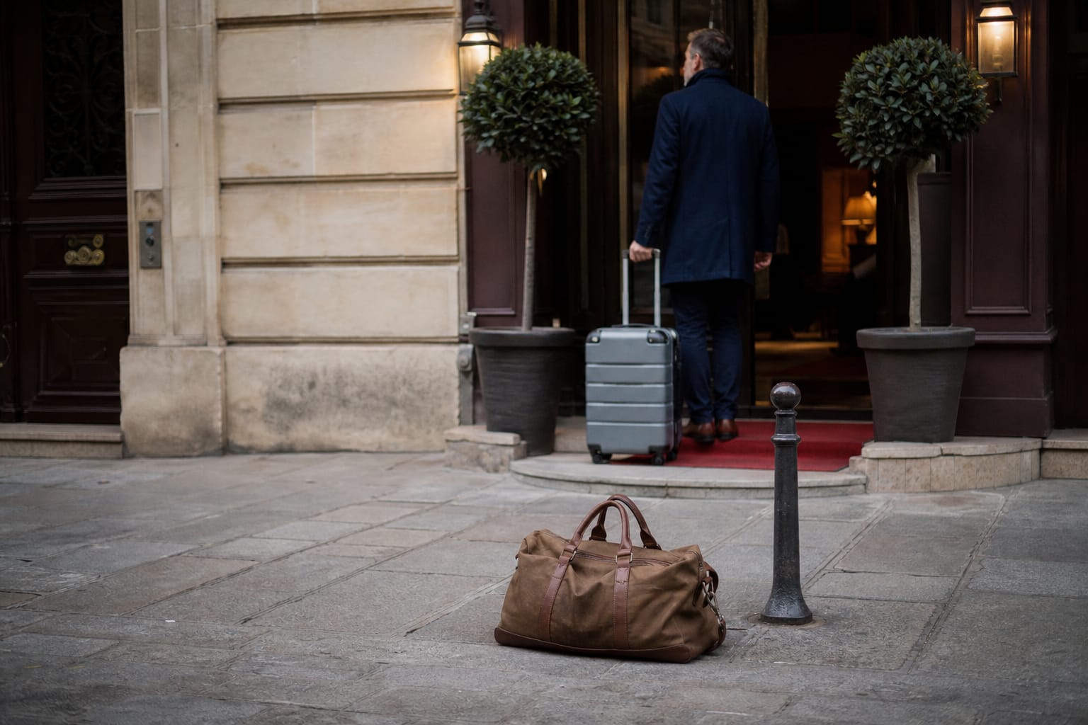 Petit sac de voyage posé devant un hôtel de centre-ville